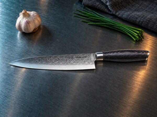 Shokutsū gyuto kokkekniv på et kokkebord i rustfrit stål